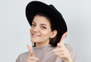 Smiling happy woman pointing at the camera with both hands and her head tilted to the side with a playful expression and focus to her face over white