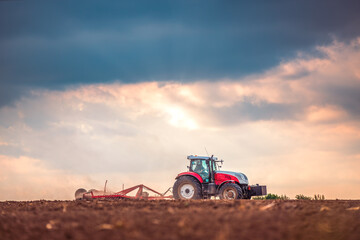 Obraz premium Farmer in tractor preparing land with seedbed cultivator