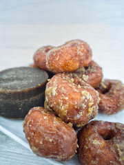 Keria gula melaka or doughnut glazed in palm sugar, made from sweet potatoes with a block of palm sugar. Selective focus points. Blurred background