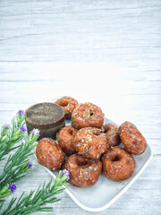 Keria gula melaka or doughnut glazed in palm sugar, made from sweet potatoes with a block of palm sugar. Selective focus points. Blurred background
