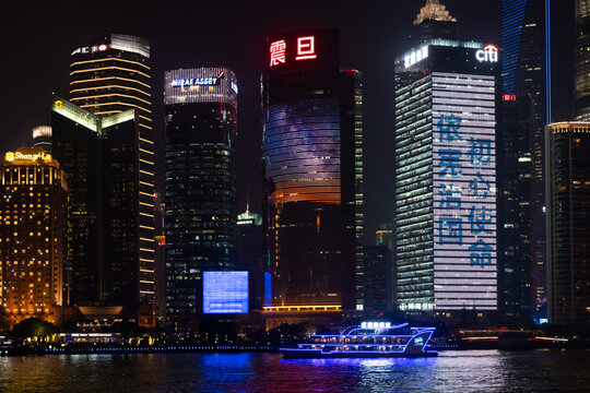 Night cityscape of Shanghai view from Bund Waitan waterfront. Neon lights of tourist ship at river water with blurry reflections and lights of skyscrapers landmarks. Shanghai, China, 12 04 2019