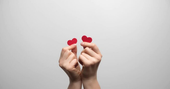 Women's hands with small hearts on a light background