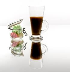 Colorful marshmallows candy and coffee in a glass cup with reflection isolated on white