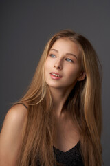 Naklejka premium Natural portrait of young beautiful teen age girl with long straight hair. Female model studio shot against grey background. Pretty girl