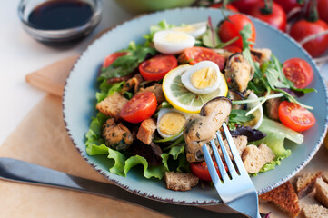 Salad with mussels, tomatoes, eggs, arugula, spinach, basil, lemon and croutons. Seafood salad with vine sauce