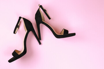 Sexy women black sandals with high-heeled stilettos on a pink background. Flat lay with copy space