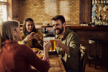 Cheerful man toasting with friends while having lunch in a pub.
