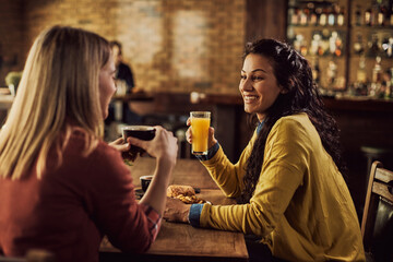 Happy female friends enjoying while talking in a pub.