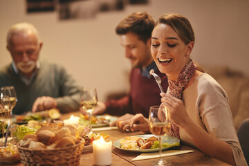 Happy woman eating while having meal with her family at dining table.