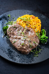Modern style traditional braised Italian ossobuco alla Milanese with saffron risotto and baby broccoli in white wine meat sauce served on a Nordic design plate with copy space