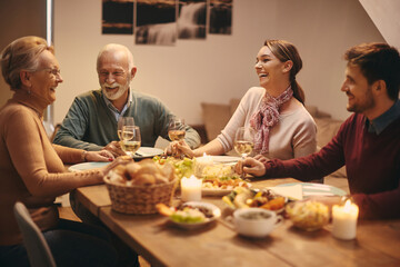 Happy family enjoying in conversation and drinking wine during a meal at dining table.
