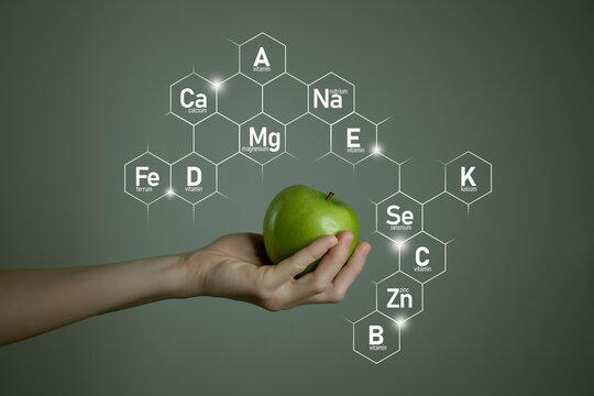 Woman`s hand holding green apple, microelement icons in molecular hexagons on grey background. Weight Loss concept template for product design.