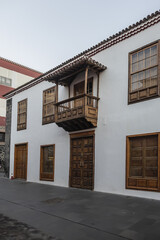 Facade of old building with a wooden balcony on a street in Spanish town Puerto de la Cruz on a sunny day. Puerto de la Cruz town, Tenerife, Canary Islands, Spain.