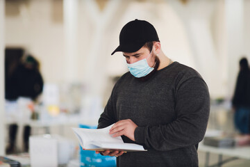 Man learning studying reading book in library during coronavirus covid19 pandemic, wearing...