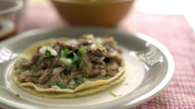 Beef barbacoa taco and glass cup of hot sauce on a table