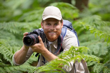 man holding camera take photo in forest