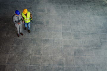 Aerial view of architect and construction worker standing on site and discussing about project.