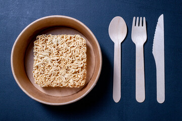 Chinese noodle soup on the kitchen table. Disposable wooden cutlery for eating instant meals.