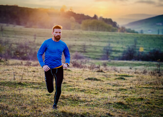 trail runner running on hill at sunset