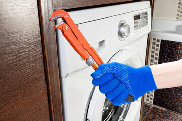 washer repair service concept. technician worker holding work tool in front of broken washing machine