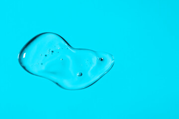 Clear liquid gel smear isolated on light blue background. Top view. Body and face care spa cosmetic concept. Transparent serum or hyaluronic acid texture. Banner with copy space