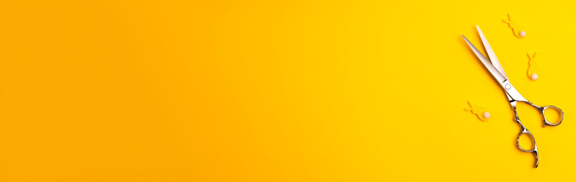 Banner template flat lay of professional hair cutting shears and bannies on yellow background Hairdresser salon equipment concept with copy space Selfcare on Easter holidays lockdown time