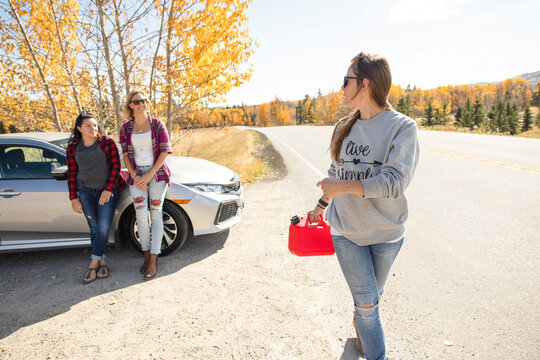 Women Walking To Get Gasoline For Broken Down Car