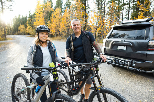 Couple with SUV preparing to go for a bike ride in forest