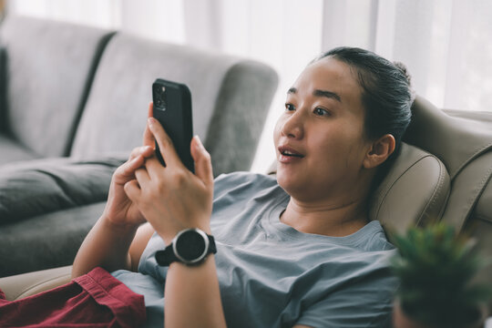 Excited happy Asian woman looking at phone screen, celebrating online win, overjoyed young female screaming with joy, holding smartphone, reading good news in unexpected message or email.