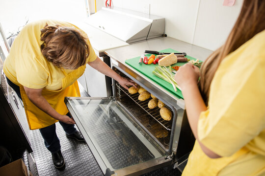 Food Truck Worker Checking On Potatoes In Oven