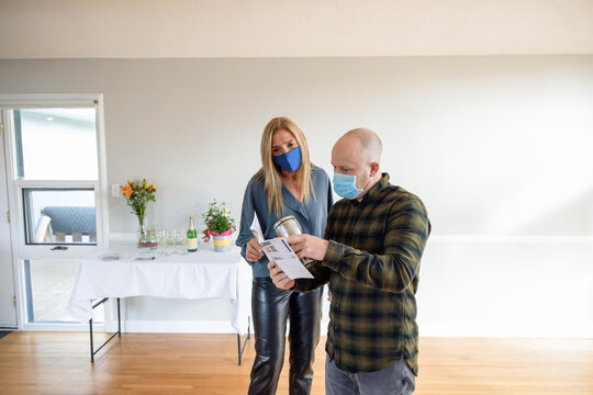 Realtor and client in face masks looking at brochure at open house
