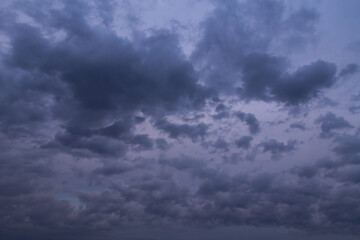 Fototapeta na wymiar Dark blue violet twilight night storm sky with many fluffy clouds