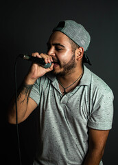 Young singer with microphone recording song in studio