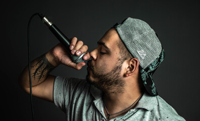 Young singer with microphone recording song in studio