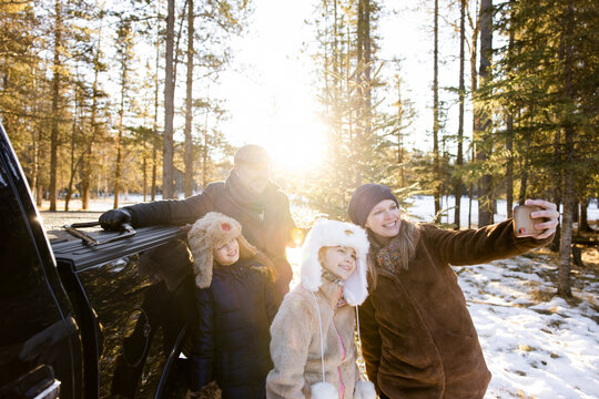 Woman taking selfie with family in snowy woods
