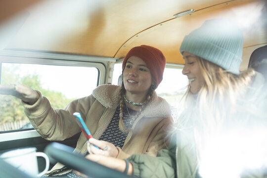 Young women friends using smart phone inside camper van