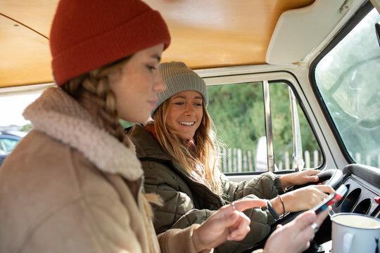 Young women friends using smart phone in van