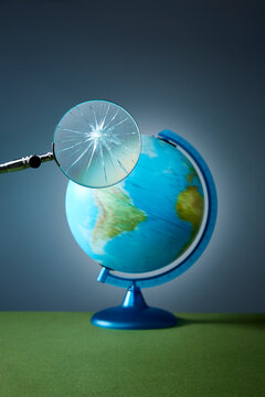 Broken magnifying glass over spinning globe