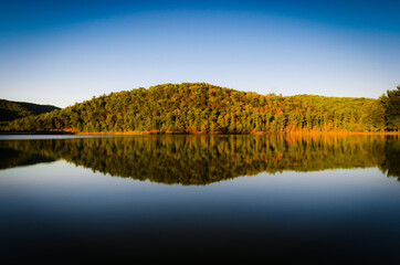 A mirror-like reflection of a foothill around Shenandoah National Park bathing in sunset, evening light, in Lake Arrowhead  in Luray.