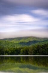 Fototapeta na wymiar The movement of clouds as the sky clears up after a period of rain at Lake Arrowhead near Luray, Virginia looking towards Shenandoah National Park.