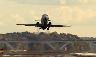  A passenger Airplane is taking off from the runway of an airport at sunset. The exhaust and...