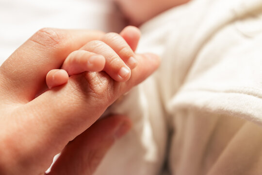 Mother holding the hand of her newborn baby