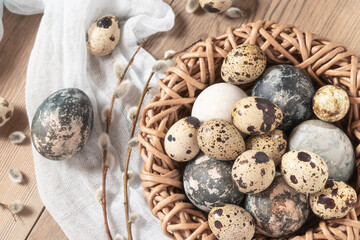 Fototapeta premium Easter composition - Easter eggs painted with natural dyes in a wicker nest on a wooden table