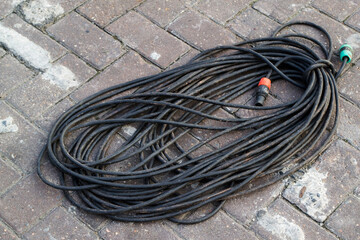 Black cord pile tangled in black on a concrete background