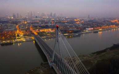 Fototapeta na wymiar Illuminated cityscape of Warsaw with Vistula river and Swietokrzyski Bridge at dusk, Poland