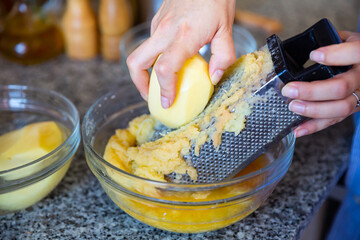 Preparation of homemade vegetable pancakes, grating raw potato
