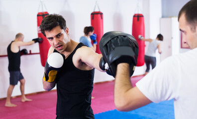 Portrait of tired young active sportsmen competing in boxing gloves