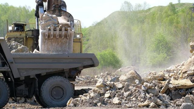 Video of excavator loads stones onto a dump truck on a open pit