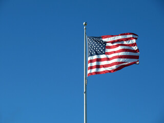 Red white and blue USA flag waving in the breeze on a blue sky day