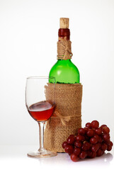 Red wine in glass with grapes and bottle.
